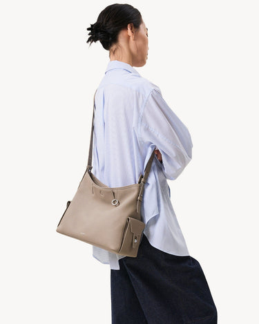Medium Yore Hobo Bag in Cobble Grain textured leather, worn over the shoulder by a woman in a blue striped shirt.