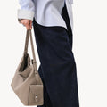 Medium Yore Hobo Bag in Cobble Grain leather, held by a person wearing a blue pinstripe shirt and dark jeans.