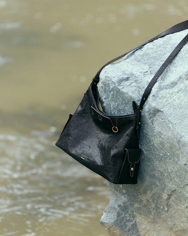 Medium Yore Hobo Bag in Onyx: Vegetable-tanned leather hobo bag with white stitching and adjustable strap.