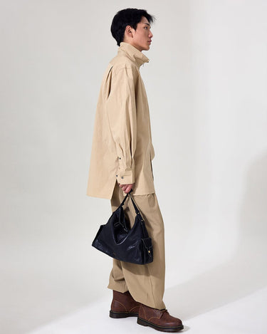 Medium Yore Hobo Bag in Onyx, made from vegetable-tanned leather, held by a man in neutral tones.