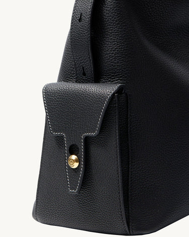 Medium Yore Hobo Bag in Onyx Grain leather with a gold clasp on a flap pocket.