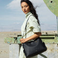 Medium Yore Hobo Bag in Onyx Grain full-grain leather, worn by a woman in a light green shirt.