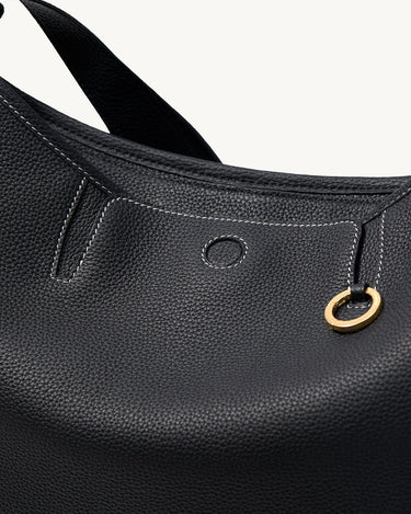 Black pebbled leather hobo bag with white stitching and a gold ring detail.