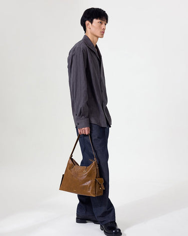 Medium Yore Hobo Bag, Sandal. Vegetable-tanned leather hobo bag with external pockets, worn by a model.