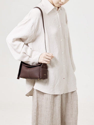 Burgundy Mini Drippy Roof Bag made of full-grain leather with gold hardware and white stitching, worn by a person.
