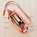 Open pink Mini Drippy Roof Bag showcasing organized contents: iPhone 15, notebook, wallet, lipstick, hand cream, and AirPods.