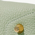 Close-up of light green full-grain leather bag with gold hardware featuring 'Songmont' logo.
