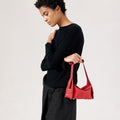 Red full-grain leather Mini Drippy Roof Bag with white stitching and a unique angular design, held by a woman.