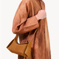 Mini Drippy Roof Bag in Sea Buckthorn nubuck leather with contrasting smooth leather details and visible stitching, worn by a woman in a brown dress.