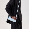 Light blue full-grain leather Mini Drippy Roof Bag with gold hardware, worn crossbody.