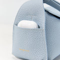 Light blue full-grain leather Mini Drippy Roof Bag with gold 'Songmont' logo and earbud case in front pocket.