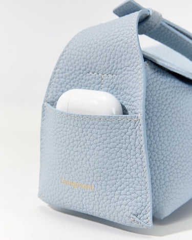 Light blue full-grain leather Mini Drippy Roof Bag with gold 'Songmont' logo and earbud case in front pocket.