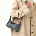 Mini Drippy Roof Bag in dark grey pebbled leather with white stitching and gold hardware, worn with a trench coat.