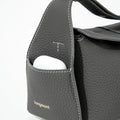 Mini Drippy Roof Bag in Stardust grey pebbled leather with white stitching and an exterior pocket holding white earbuds.