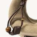 Tan suede Mini Luna Airpods case with brown leather accents, braided strap, and tiger's eye bead detail.