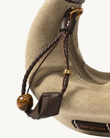 Tan suede Mini Luna Airpods case with brown leather accents, braided strap, and tiger's eye bead detail.