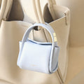Sky Mini Song AirPods Case in textured leather with gold hardware, attached to a beige tote bag.