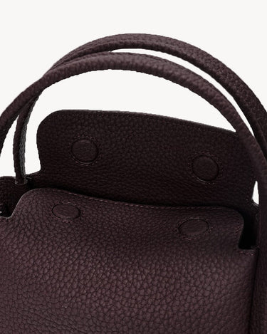 Close-up of the burgundy Mini Song Bag showing its pebbled leather texture, double handles, and interior flap.