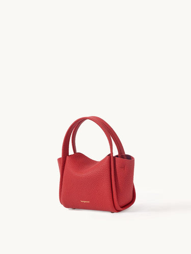 Red pebbled leather Mini Song Bag with curved top handle and gold foil logo. A chic, compact handbag for seasonal styling.