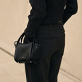 Mini Song Bag in Onyx black full-grain leather with dual top handles and silver hardware.