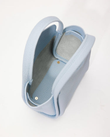 Sky blue pebbled leather Mini Song Bag with grey interior and gold snap closure, open top view.