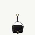 Black vegetable-tanned leather Mini Yore AirPods case with white stitching and gold hardware.