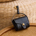 Mini Yore black leather AirPods case with white stitching and gold clasp.