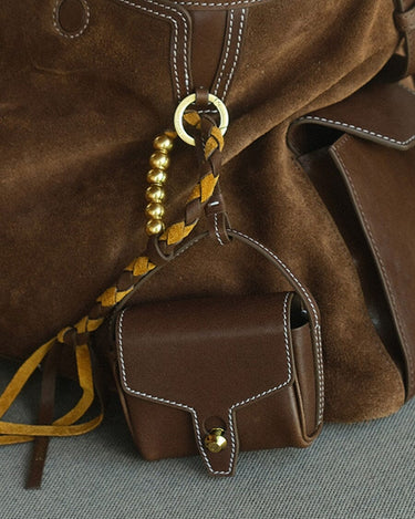 Mini Yore AirPods Case in Sandal color, made of vegetable-tanned leather, attached to a suede bag.