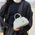 Celeste Mini Yore Bowling Bag crafted from pebbled full-grain leather with silver hardware, held by a woman in a desert.