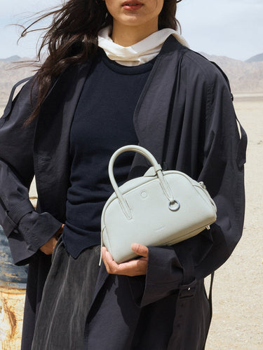 Celeste Mini Yore Bowling Bag crafted from pebbled full-grain leather with silver hardware, held by a woman in a desert.