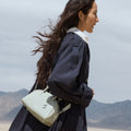 Mini Yore Bowling Bag in Celeste carried by a woman in a desert setting. Features full-grain leather and silver hardware.