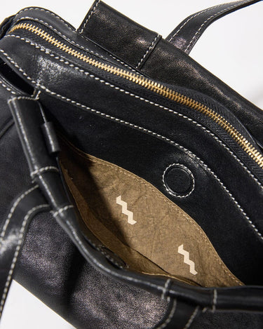 Black Mini Yore Duffle Bag interior with gold zipper, contrast stitching, and zigzag patterned pocket.