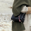 Mini Yore Duffle Bag in Onyx, black leather crossbody bag with white stitching and braided charm.