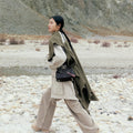 Mini Yore Duffle Bag in Onyx black leather, worn by a woman in a rocky outdoor setting.