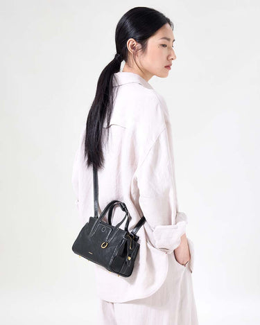 Mini Yore Duffle Bag in Onyx: black vegetable-tanned leather with white stitching and gold hardware, worn on shoulder.