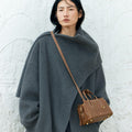Mini Yore Duffle Bag in Sandal brown vegetable-tanned leather, worn by a woman in a grey coat.