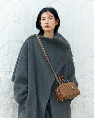 Mini Yore Duffle Bag in Sandal brown vegetable-tanned leather, worn by a woman in a grey coat.