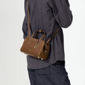 Mini Yore Duffle Bag in Sandal color, crafted from vegetable-tanned leather with gold hardware, worn crossbody.