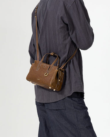 Mini Yore Duffle Bag in Sandal color, crafted from vegetable-tanned leather with gold hardware, worn crossbody.