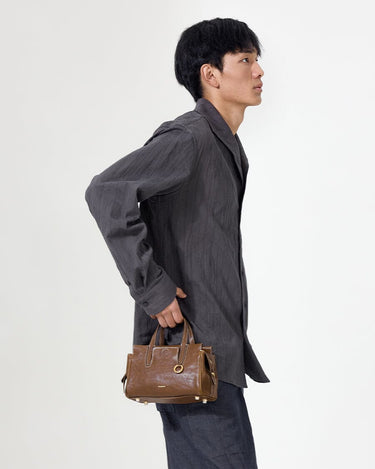 Mini Yore Duffle Bag in Sandal color, crafted from vegetable-tanned leather with gold hardware, held by a man.