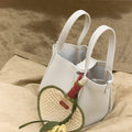 White leather Osmanthus Charm tote bag with woven heart fan charm and yellow flower detail.
