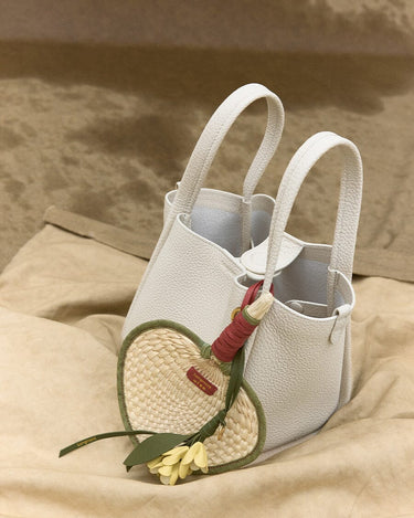 White leather Osmanthus Charm tote bag with woven heart fan charm and yellow flower detail.