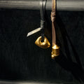 Gold abstract charm on black leather and gold prayer wheel charm on brown leather.