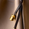 Sandal Prayer Wheel Charm with engraved golden cylinder and leather strap on pebbled leather handbag