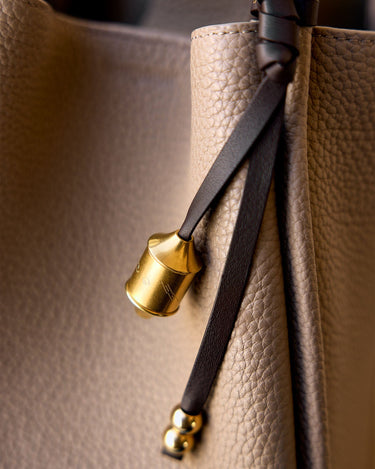 Sandal Prayer Wheel Charm with engraved golden cylinder and leather strap on pebbled leather handbag