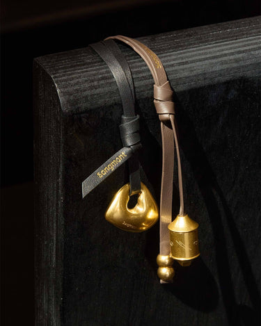 Prayer Wheel Charm: Sandal & Onyx leather straps with gold pendants. "Songmont" logo embossed.