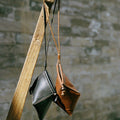 Prism Airpods Case in onyx black and sandal brown leather, featuring braided straps and sandalwood beads.