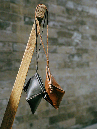 Prism Airpods Case in onyx black and sandal brown leather, featuring braided straps and sandalwood beads.