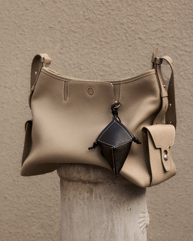 Beige full-grain leather Prism Airpods Case with dark geometric charm. Textured exterior, subtle stitching.