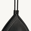 Prism Airpods Case in onyx black leather with white stitching and braided strap.